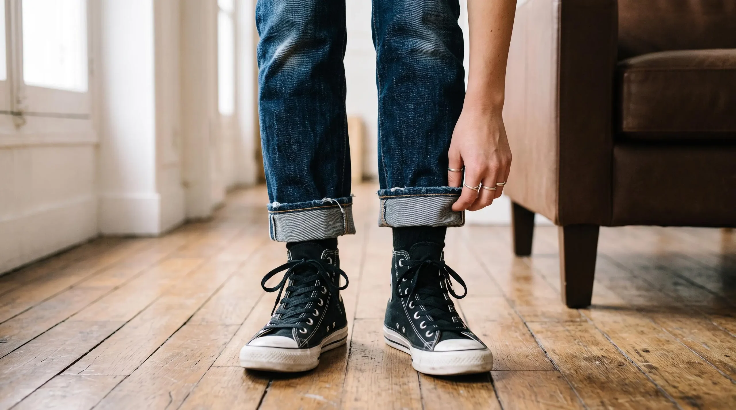 Un jean retroussé et des baskets montantes noires portés dans un intérieur lumineux.