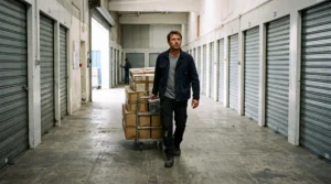 Un homme pousse un diable chargé de cartons dans le couloir d'un centre de stockage.